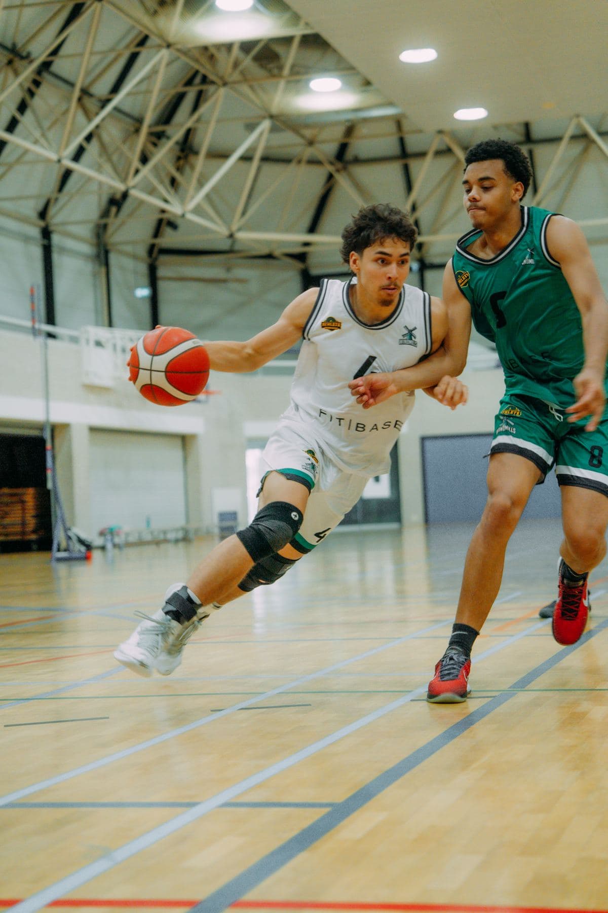Speler drijft langs zijn verdediger naar de basket