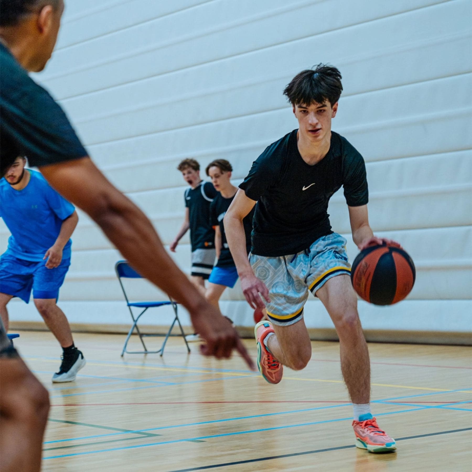 Jeugdspeler dribbelt onder druk richting de basket